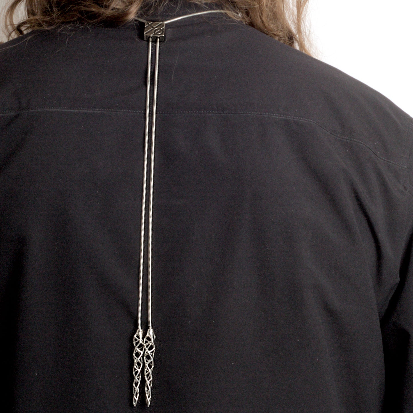 Back view of the .925 sterling silver choker/bolo-tie hybrid necklace worn by a man. In this image the bolo-tie tips hang down the man's back.