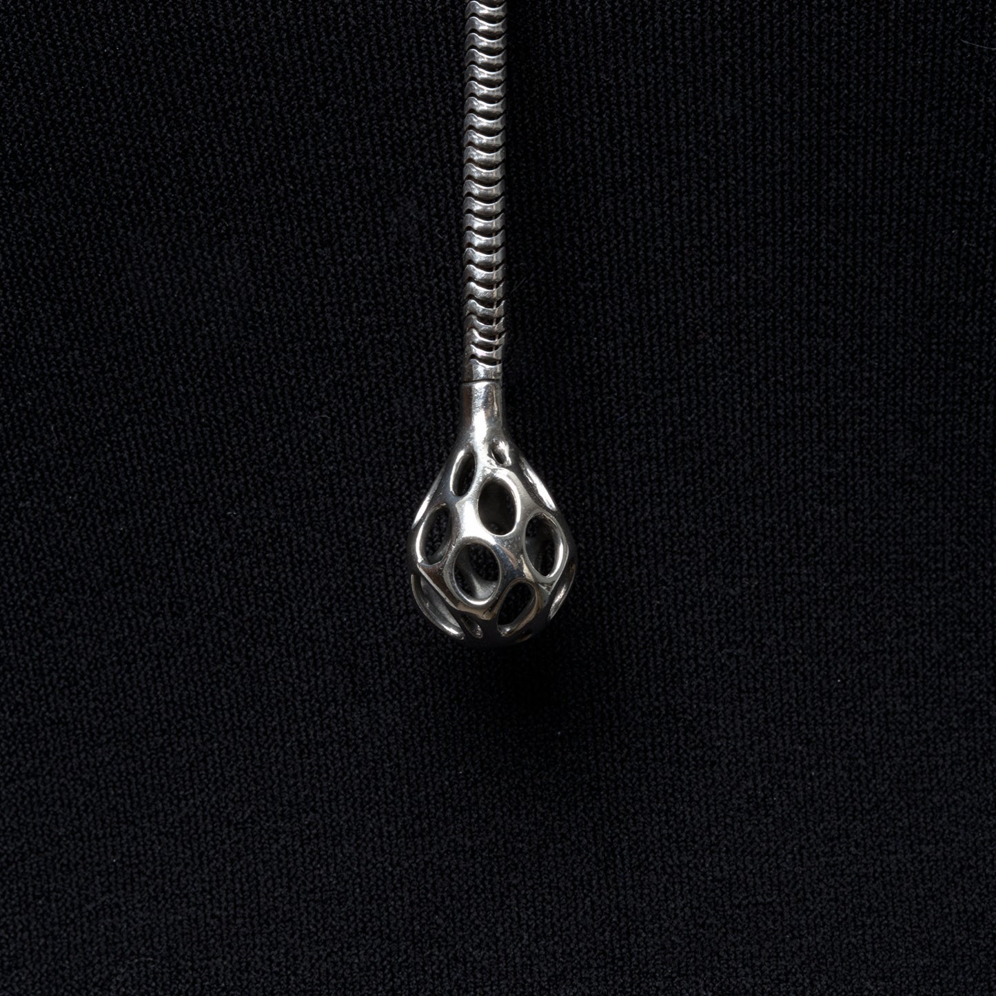 Close up detail of the sterling silver sculptural droplet emerging from the thick snake chain lariat necklace.