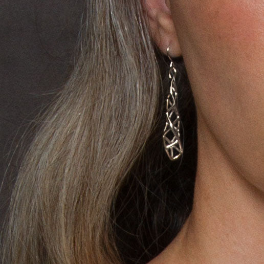 Sterling silver dimensional lattice earrings shown on the ear for scale.