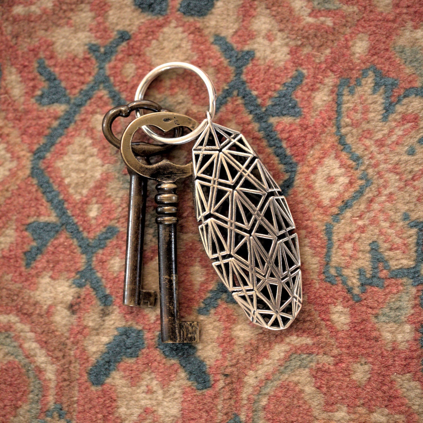 Sculptural sterling silver keychain featuring Art Deco-inspired lattice design secures antique keys.