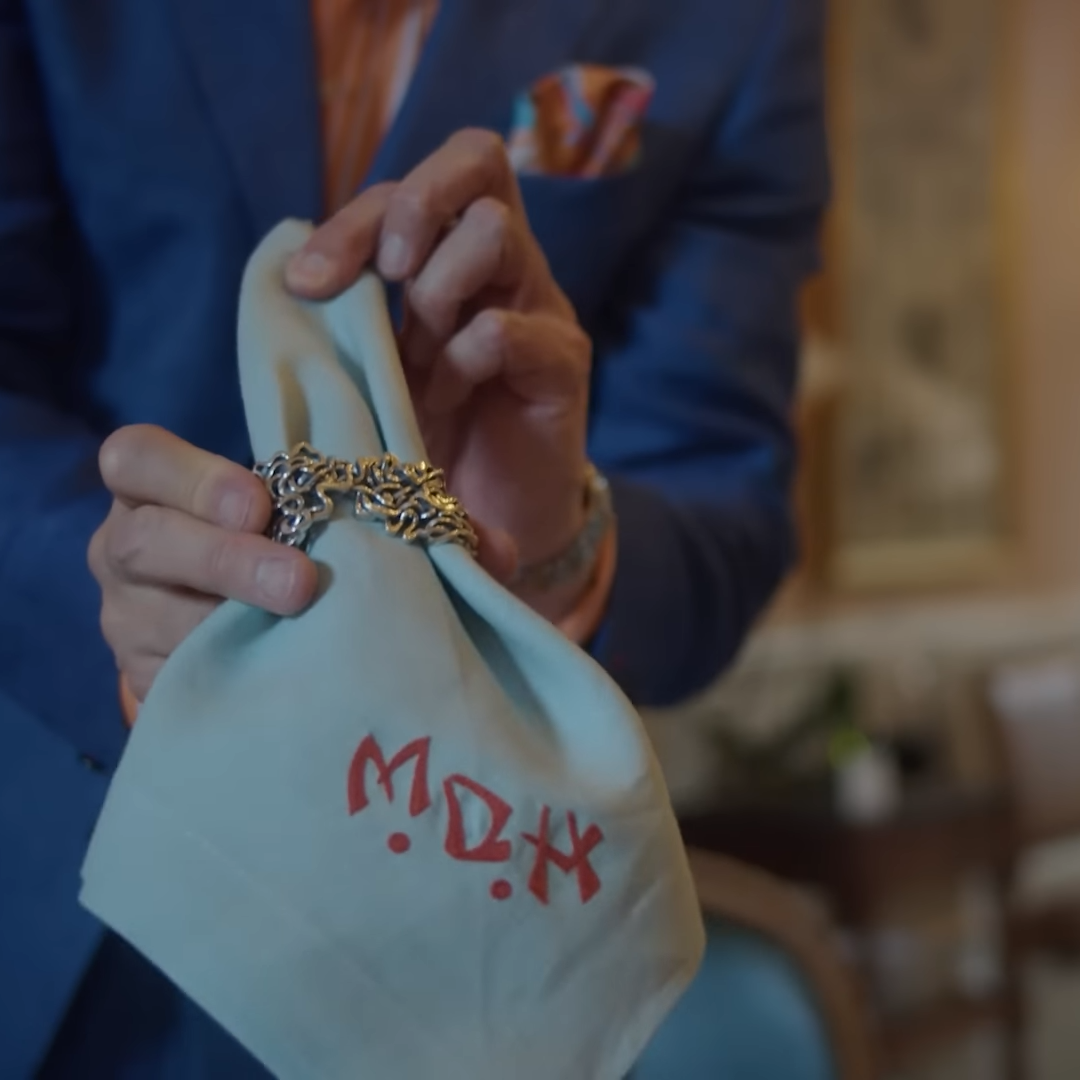 Xover0’s solid sterling silver Mississippi River Napkin Ring held by a man in a blue suit from the Homeworthy episode “HOUSE PARTY TOUR | Inside a Glamorous Progressive Dinner in New Orleans."