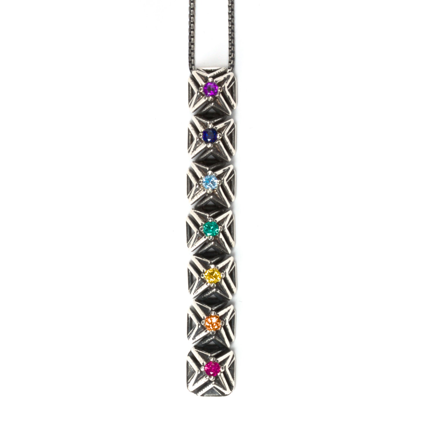 Seven rainbow colored gemstones are arranged in chakra order in this vertical bar pendant necklace. The intricate pyramid spike settings are made of contrast oxidized solid sterling silver. It is suspended from a matching box chain. 