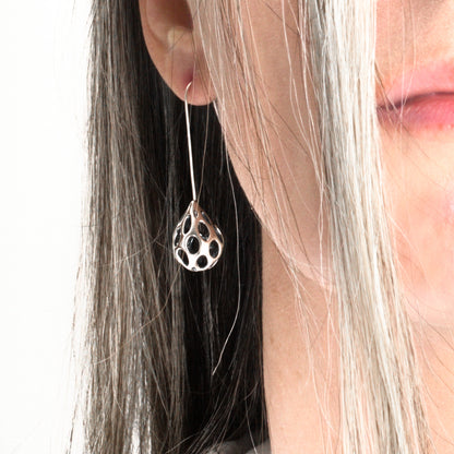 Close up of one sterling silver dangle earring on the ear for scale. They hang about one and three quarters inches from the earlobe. 