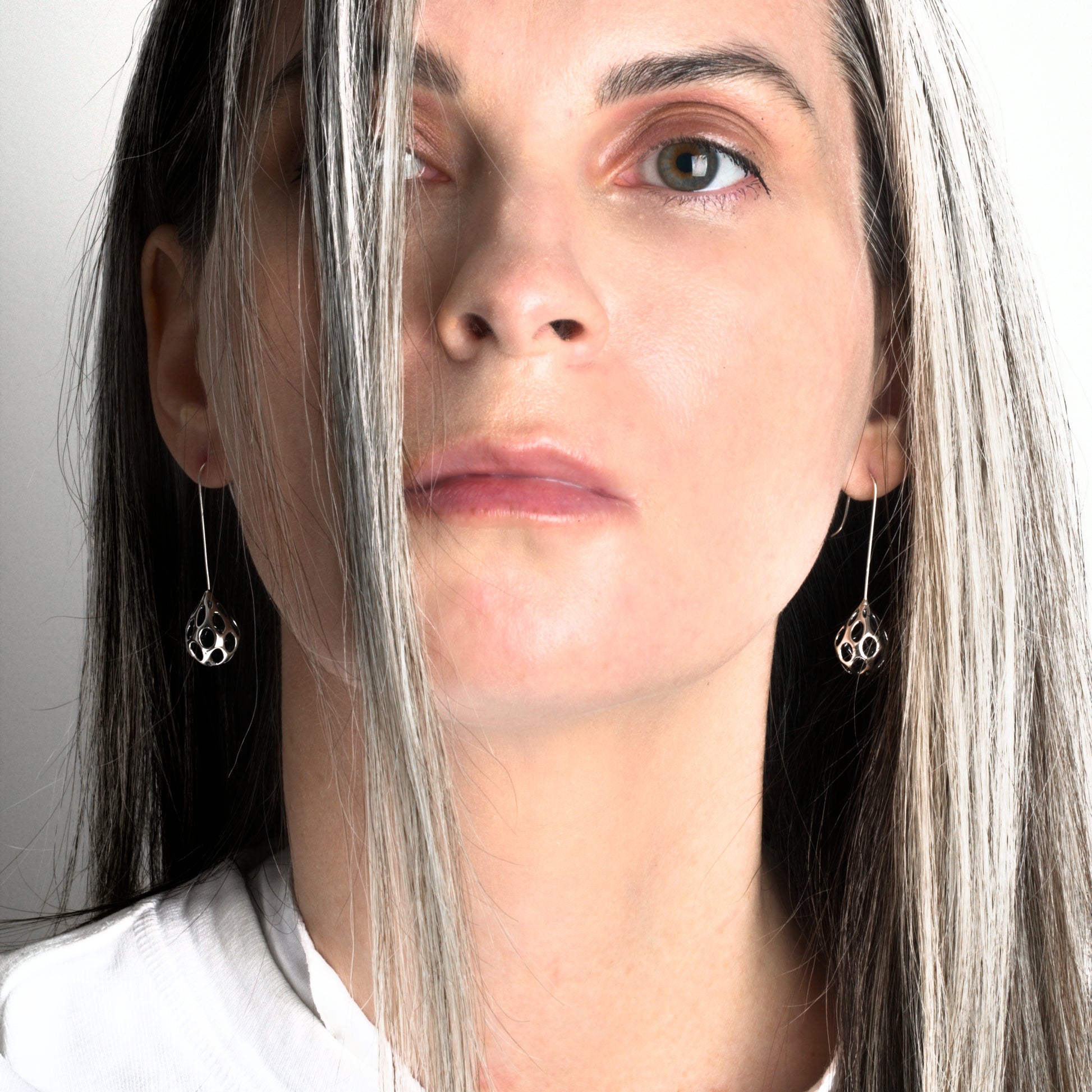 A pair of solid sterling silver drop earrings made of contrast oxidized .925 sterling silver are modeled by the designer for scale. They are hand soldered to matching hooks - all in solid sterling - no plated metals are used. 