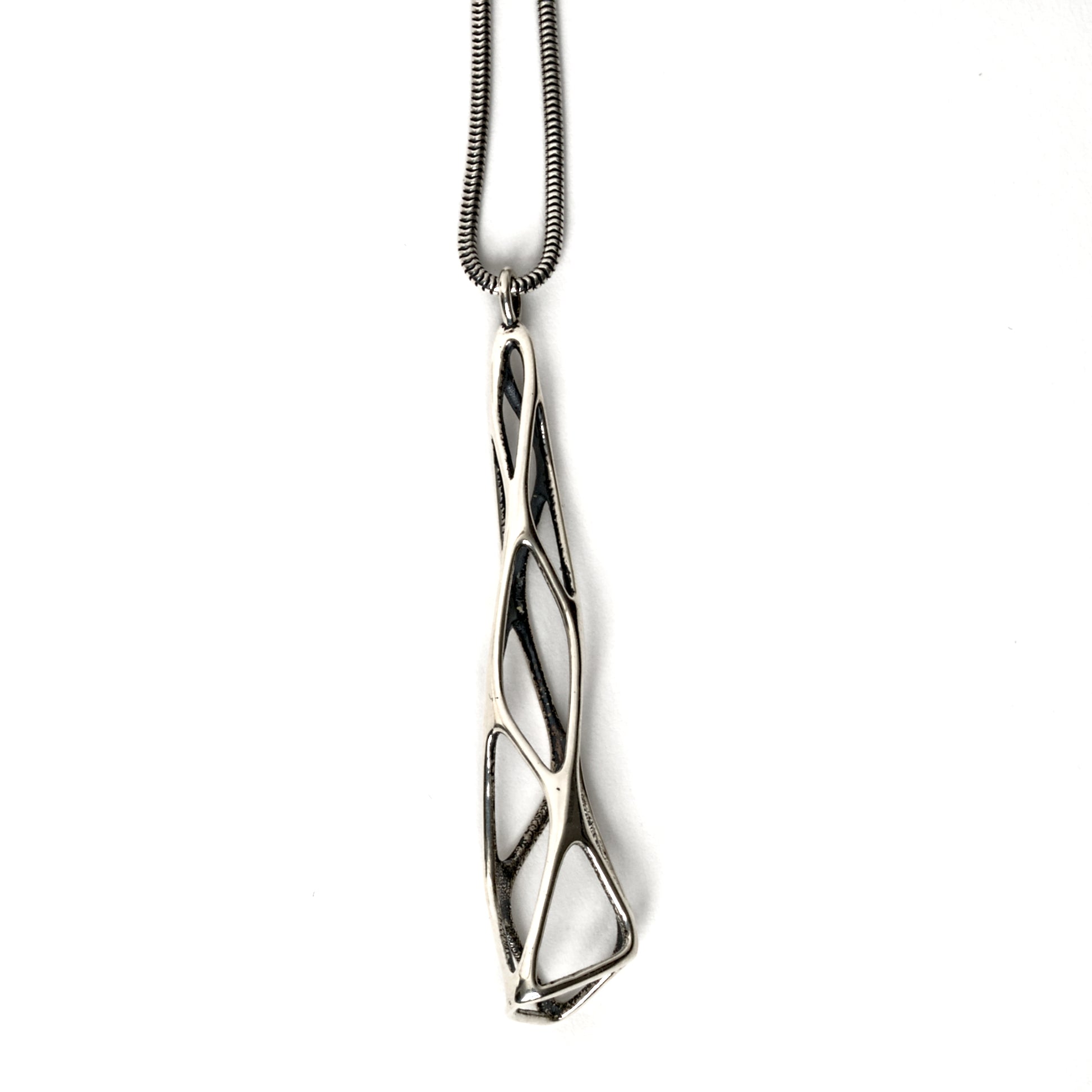 The contrast oxidized solid sterling silver "Tamarix" pendant is photographed on a white background. The outer surfaces are polished to a mirror shine. The inner surfaces of this delicate lattice are contrast oxidized for a dark matte finish. The twisting lattice is suspended from a matching snake chain. 