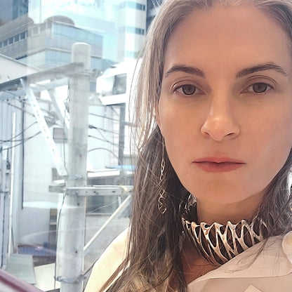 Woman wearing an edgy sterling silver choker necklace with a cityscape background.